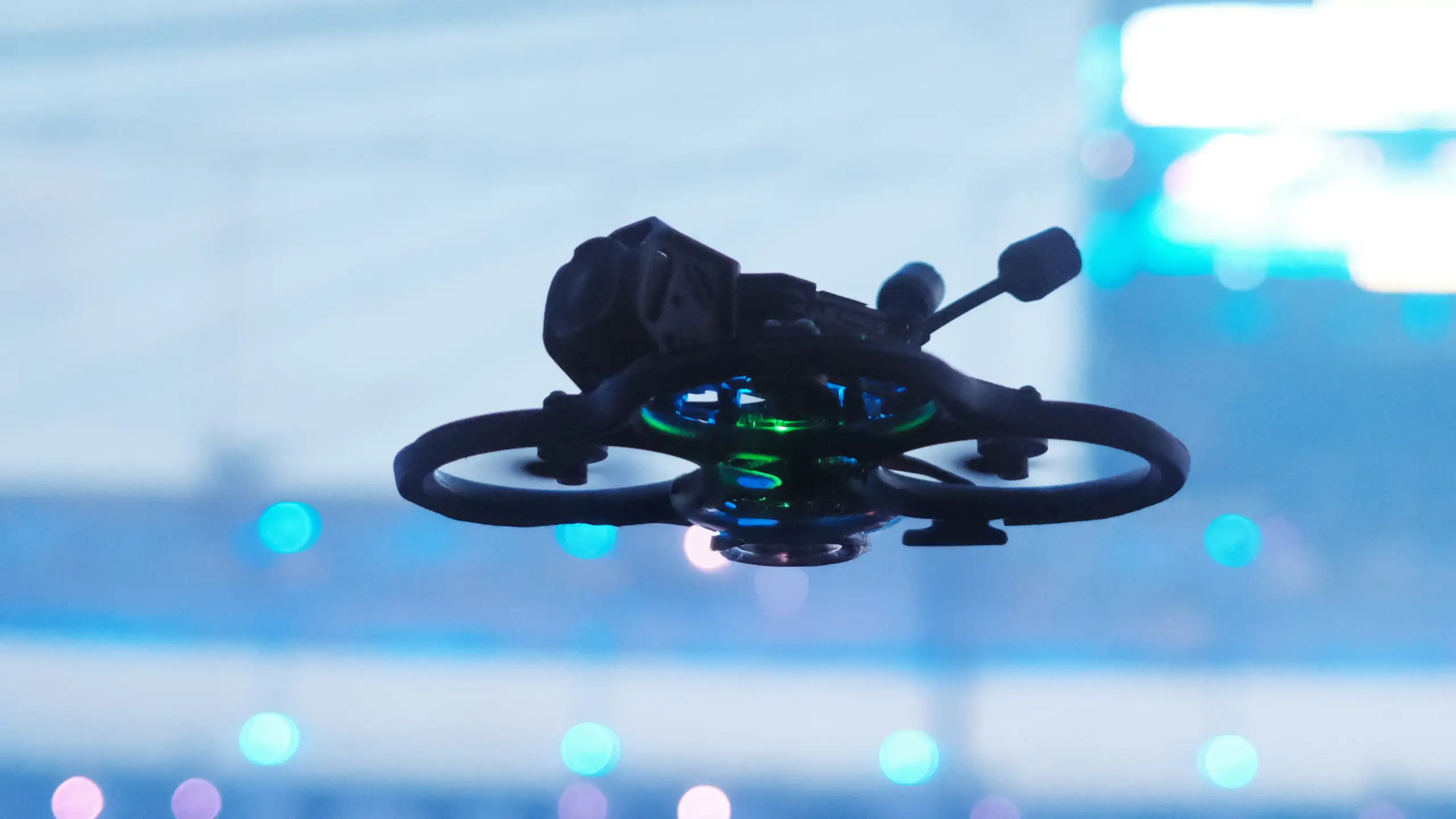 FPV-Drohne unter 150 g mit Propellerschützern im Flug über einer Arena